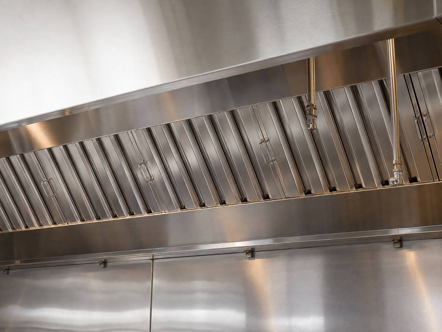 A professionally cleaned stainless-steel commercial kitchen exhaust hood